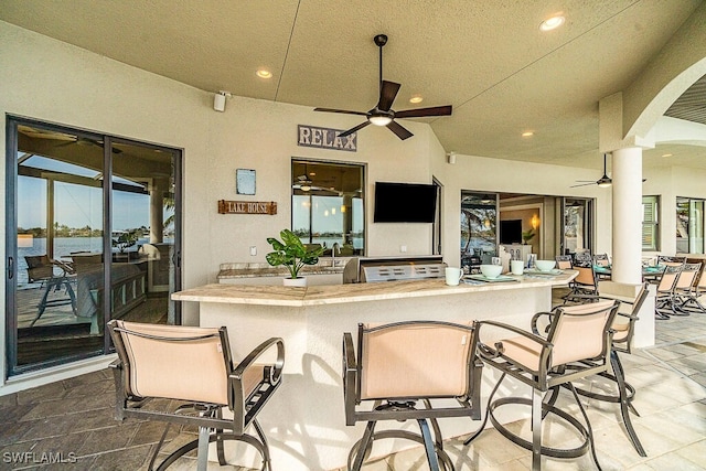 view of patio / terrace with a ceiling fan, outdoor wet bar, and a water view