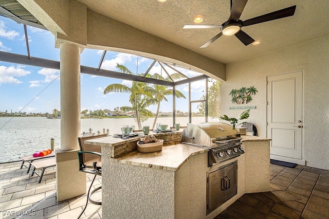 view of patio / terrace featuring a water view, area for grilling, an outdoor kitchen, glass enclosure, and outdoor wet bar