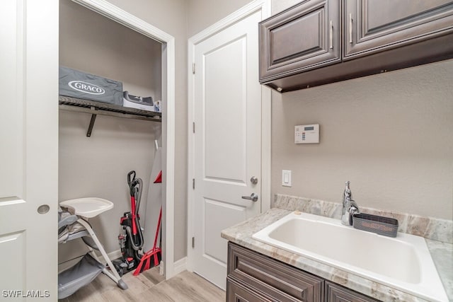 laundry room with a sink, light wood-style flooring, and baseboards