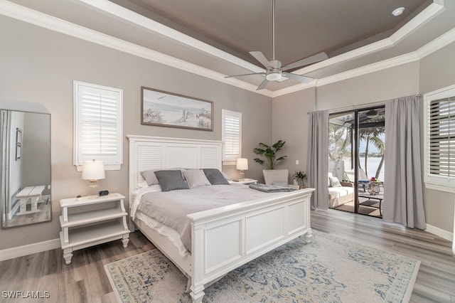 bedroom featuring baseboards, access to exterior, ornamental molding, light wood finished floors, and a raised ceiling