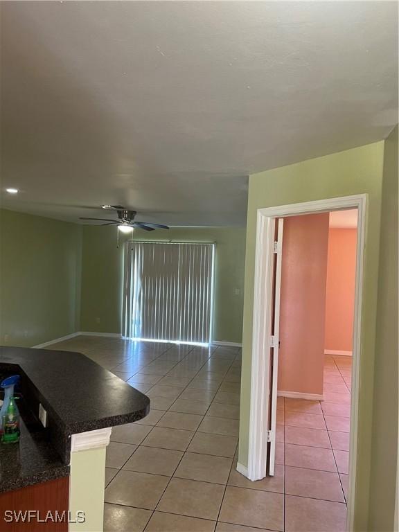 spare room with light tile patterned floors, baseboards, and a ceiling fan