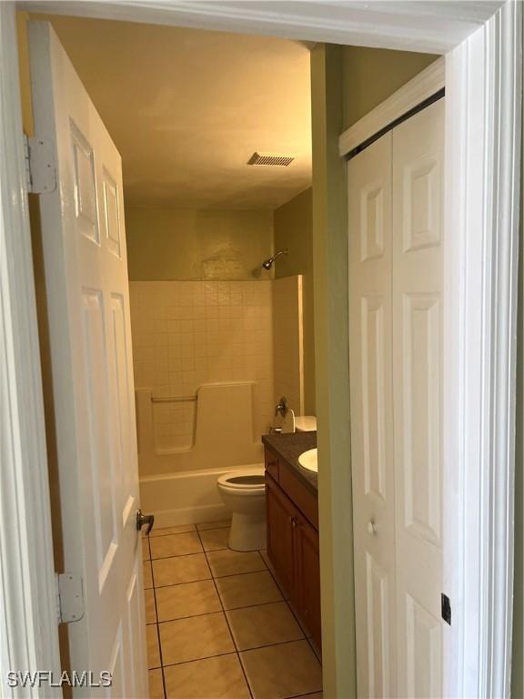 full bathroom with a closet, visible vents, toilet, vanity, and tile patterned floors