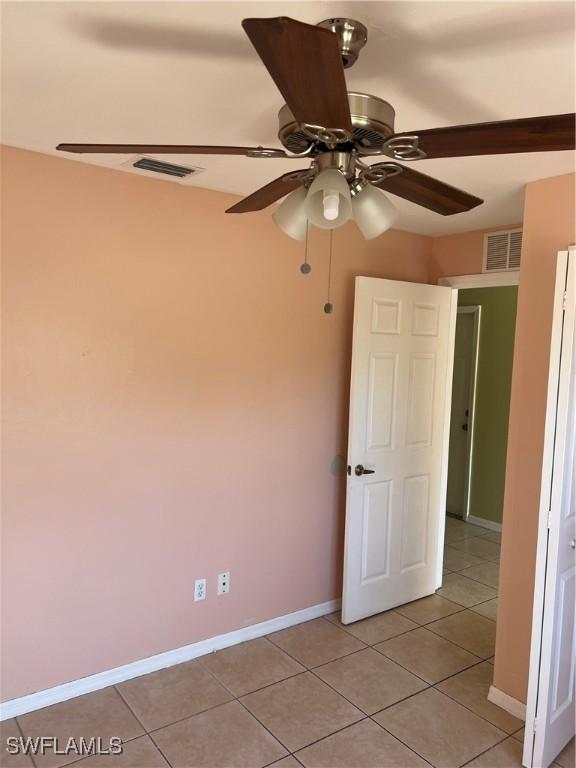 unfurnished room with light tile patterned floors, baseboards, visible vents, and a ceiling fan