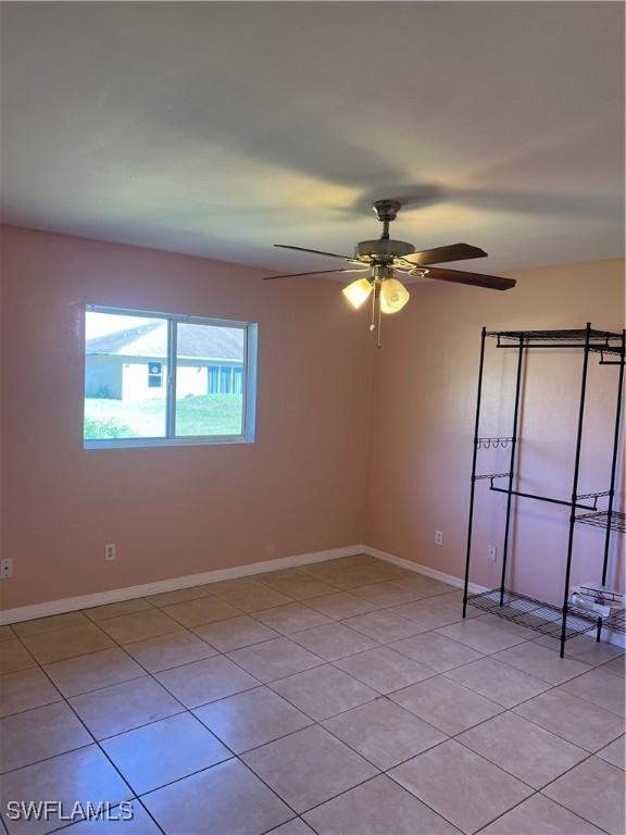 spare room with light tile patterned floors, baseboards, and a ceiling fan