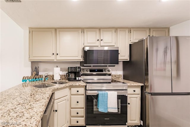 kitchen featuring stainless steel appliances, a sink, visible vents, and light stone countertops