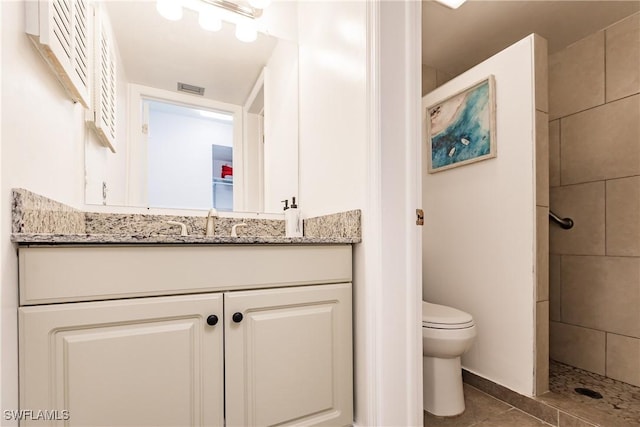 full bathroom featuring visible vents, toilet, tile patterned flooring, a tile shower, and vanity