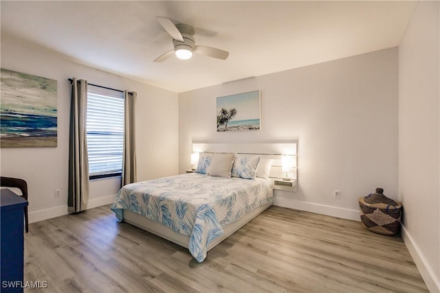 bedroom featuring ceiling fan, light wood-style flooring, and baseboards