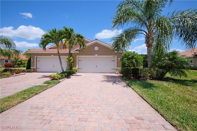 view of front of property with decorative driveway, an attached garage, a front lawn, and stucco siding