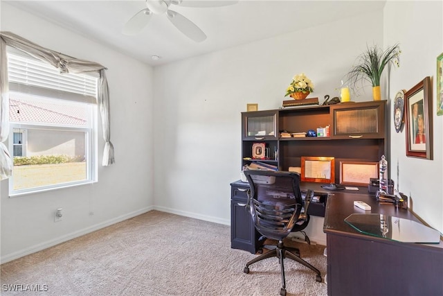 office space featuring baseboards, a ceiling fan, and light colored carpet