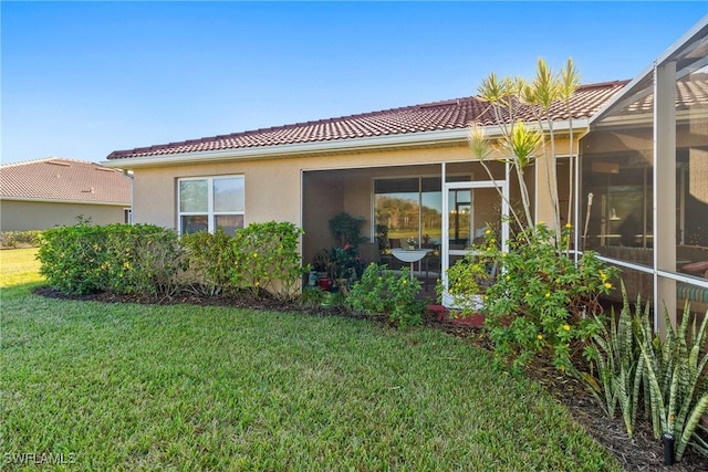 rear view of property with stucco siding, a tiled roof, and a yard