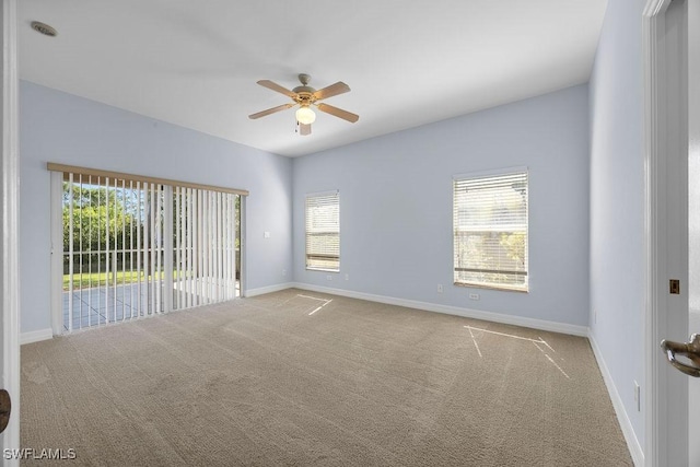 spare room featuring light carpet, ceiling fan, and baseboards