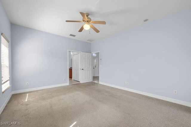 spare room featuring a ceiling fan, visible vents, light carpet, and baseboards