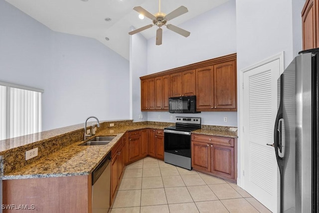 kitchen featuring stone counters, brown cabinets, stainless steel appliances, a sink, and a peninsula