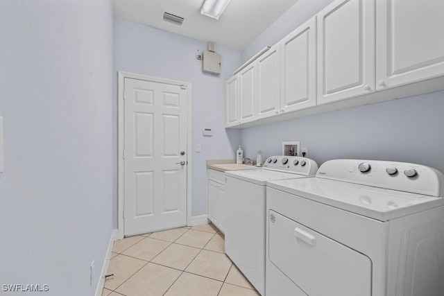 laundry room featuring light tile patterned floors, visible vents, cabinet space, separate washer and dryer, and baseboards