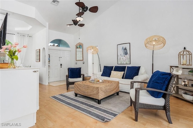 living room with a healthy amount of sunlight, light wood-style floors, visible vents, and arched walkways