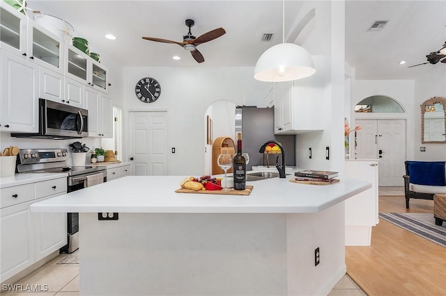 kitchen featuring ceiling fan, appliances with stainless steel finishes, glass insert cabinets, and visible vents