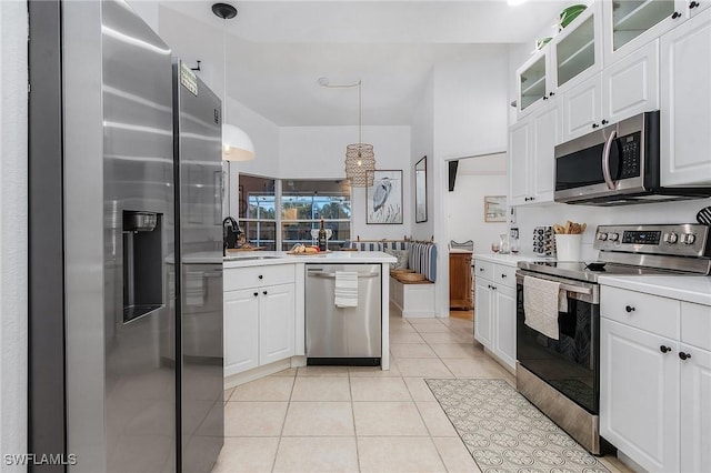 kitchen with white cabinets, light tile patterned floors, stainless steel appliances, and a sink