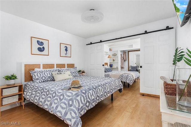 bedroom featuring light wood-type flooring and a barn door