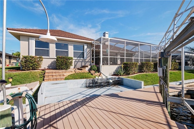 rear view of house featuring a lawn, a lanai, and stucco siding