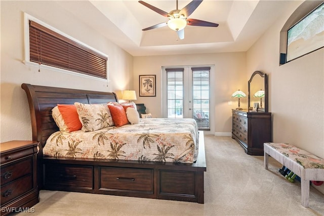 bedroom with light carpet, a raised ceiling, a ceiling fan, access to exterior, and french doors