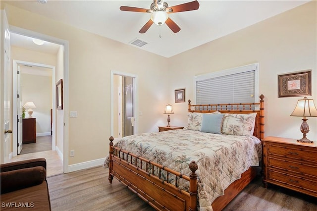 bedroom featuring a ceiling fan, visible vents, baseboards, and wood finished floors