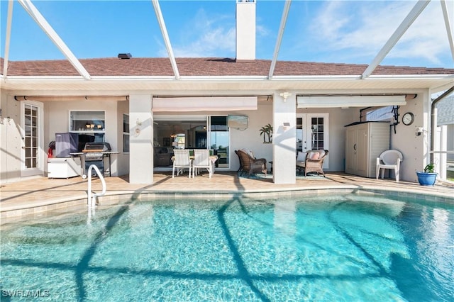 outdoor pool featuring glass enclosure and a patio