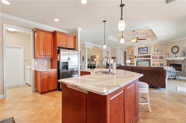 kitchen with a fireplace, a sink, open floor plan, stainless steel refrigerator with ice dispenser, and an island with sink