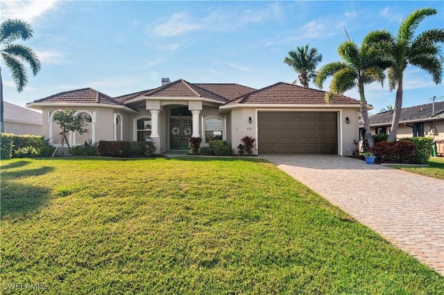 view of front of house with decorative driveway, a tile roof, stucco siding, a garage, and a front lawn