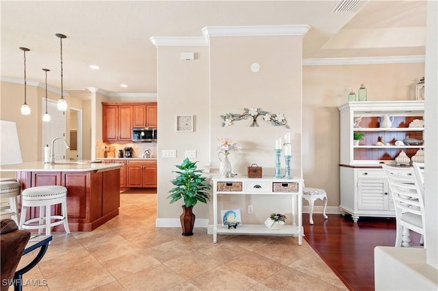 kitchen featuring stainless steel microwave, a sink, a kitchen breakfast bar, light countertops, and an island with sink