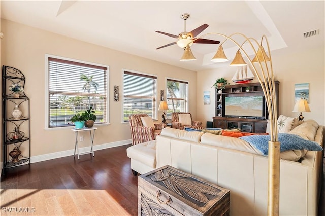 living room with baseboards, ceiling fan, visible vents, and dark wood-type flooring