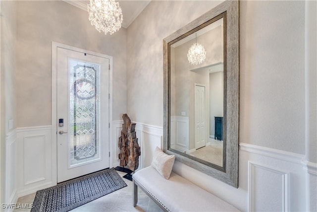 entrance foyer with a wainscoted wall, light tile patterned floors, a chandelier, and a decorative wall