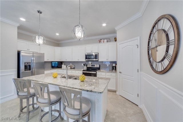 kitchen with a kitchen island with sink, stainless steel appliances, a sink, white cabinetry, and pendant lighting