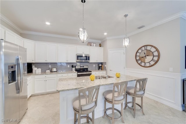 kitchen featuring pendant lighting, stainless steel appliances, a kitchen island with sink, and white cabinetry