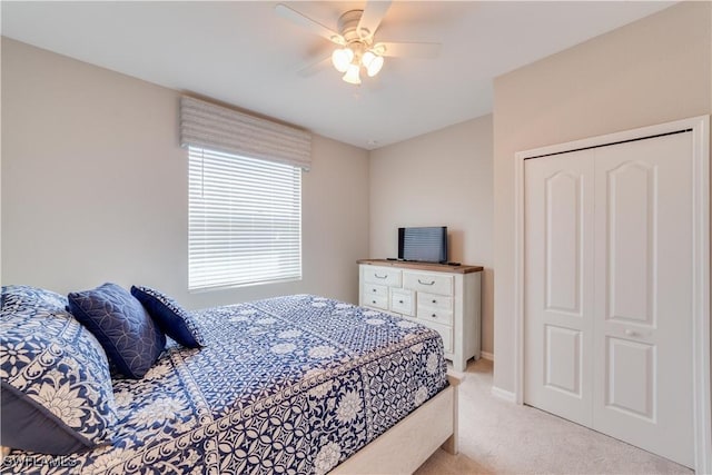 bedroom with a ceiling fan, a closet, light colored carpet, and baseboards