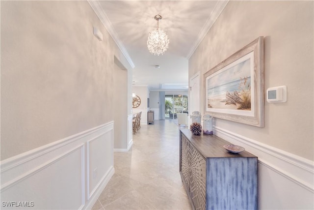 hallway featuring ornamental molding, wainscoting, an inviting chandelier, and a decorative wall