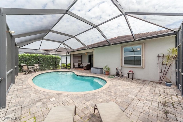 pool featuring glass enclosure, a patio area, and outdoor lounge area