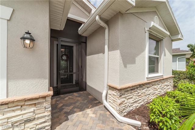 property entrance featuring stone siding and stucco siding