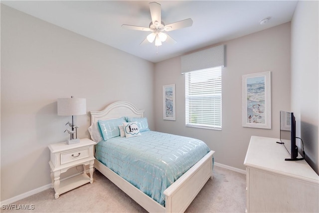 bedroom with a ceiling fan, light carpet, and baseboards