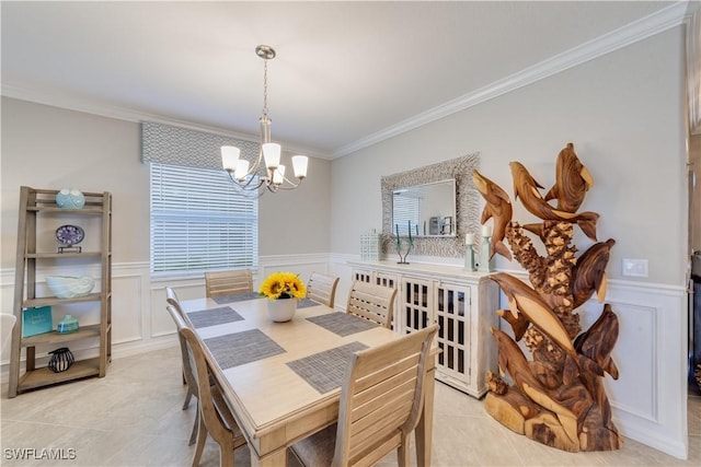 dining space with a wainscoted wall, light tile patterned flooring, a notable chandelier, and crown molding