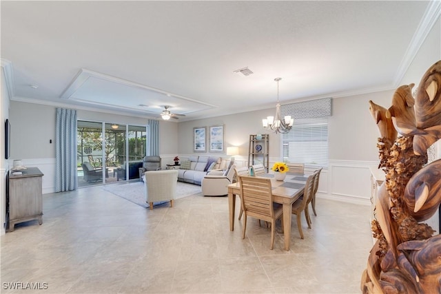 dining area featuring a decorative wall, ceiling fan with notable chandelier, visible vents, ornamental molding, and wainscoting