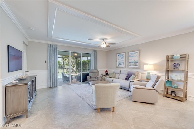 living area with a wainscoted wall, ornamental molding, visible vents, and a ceiling fan