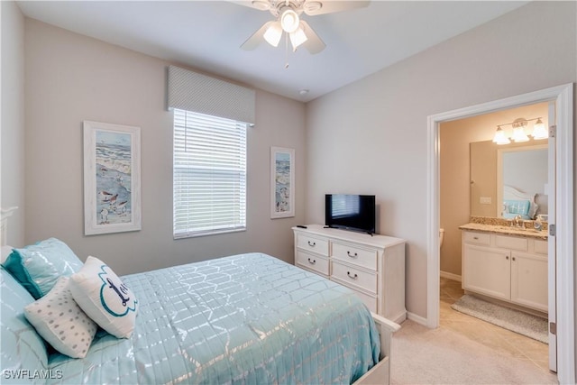 bedroom featuring light colored carpet, ceiling fan, baseboards, and ensuite bathroom