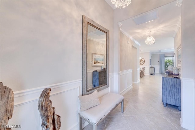 corridor featuring a chandelier, ornamental molding, wainscoting, and light tile patterned flooring