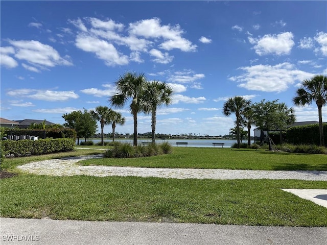 surrounding community with a water view and a lawn