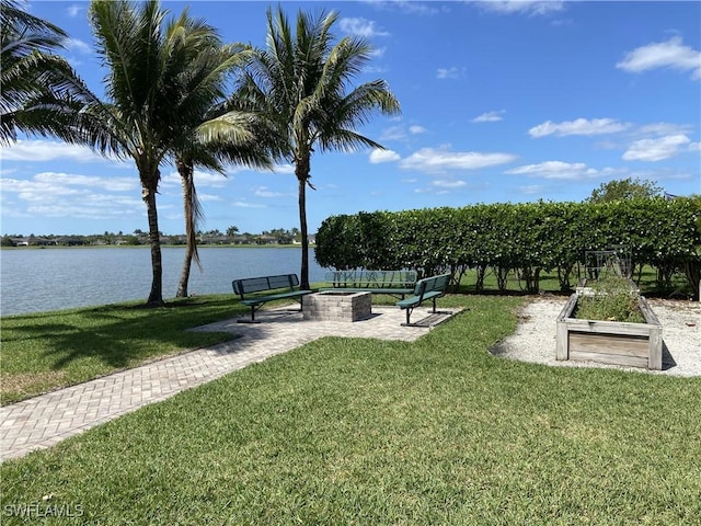 view of home's community with a patio, a lawn, and a water view