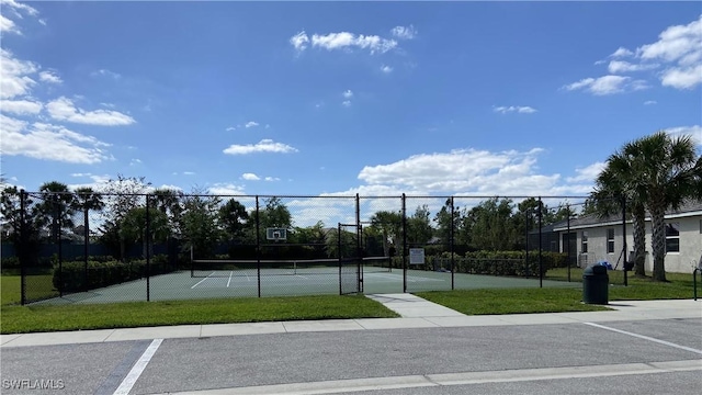 view of tennis court featuring a yard and fence