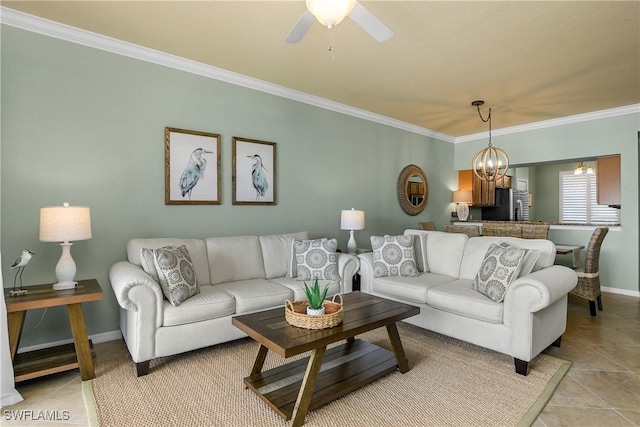 living area featuring ceiling fan with notable chandelier, baseboards, crown molding, and light tile patterned flooring