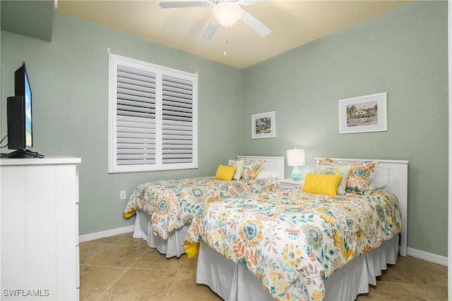 tiled bedroom with ceiling fan and baseboards