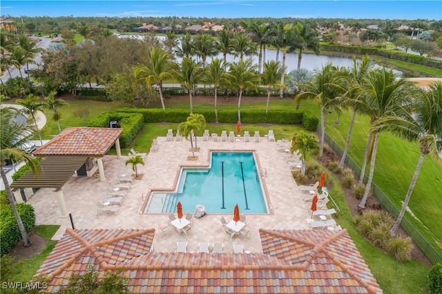 pool featuring a patio, a yard, a water view, and fence