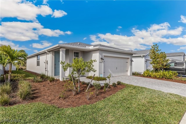 single story home featuring decorative driveway, an attached garage, a front yard, and stucco siding